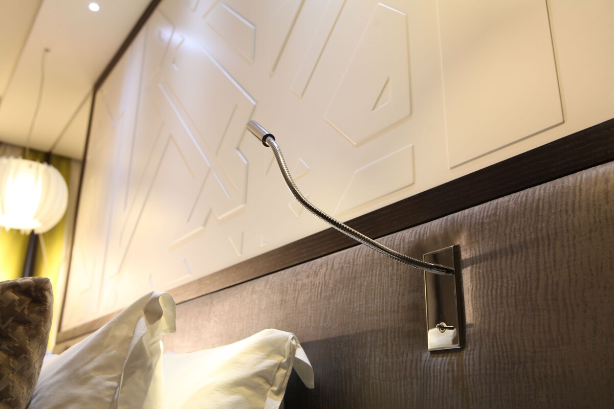 Primer plano de un dispensador de toallas montado en la pared con una manguera flexible, una lámpara y un enchufe.