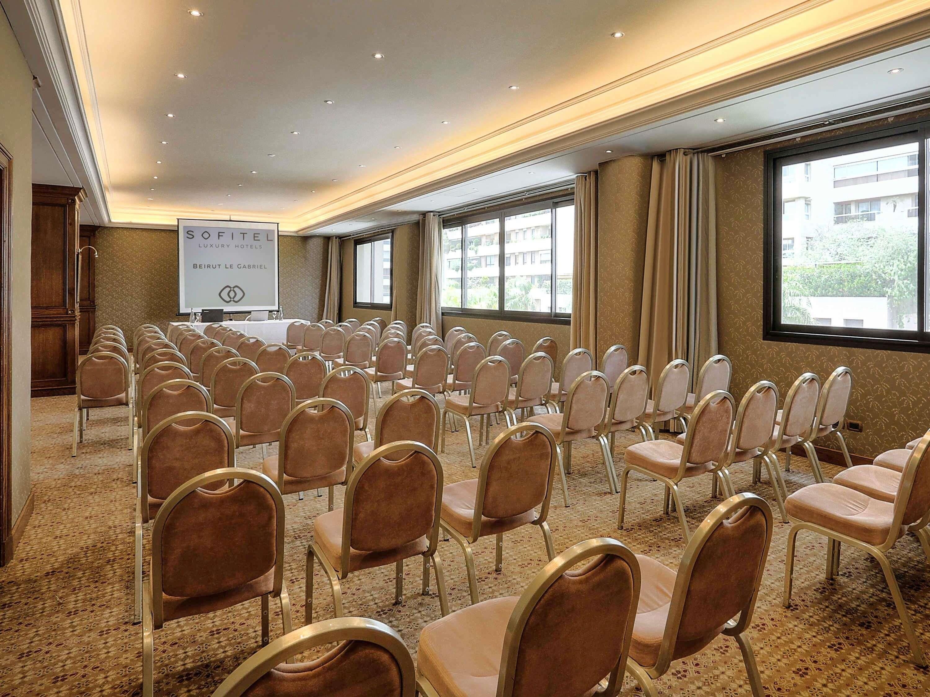 A conference room with rows of chairs, a podium, and a banner.