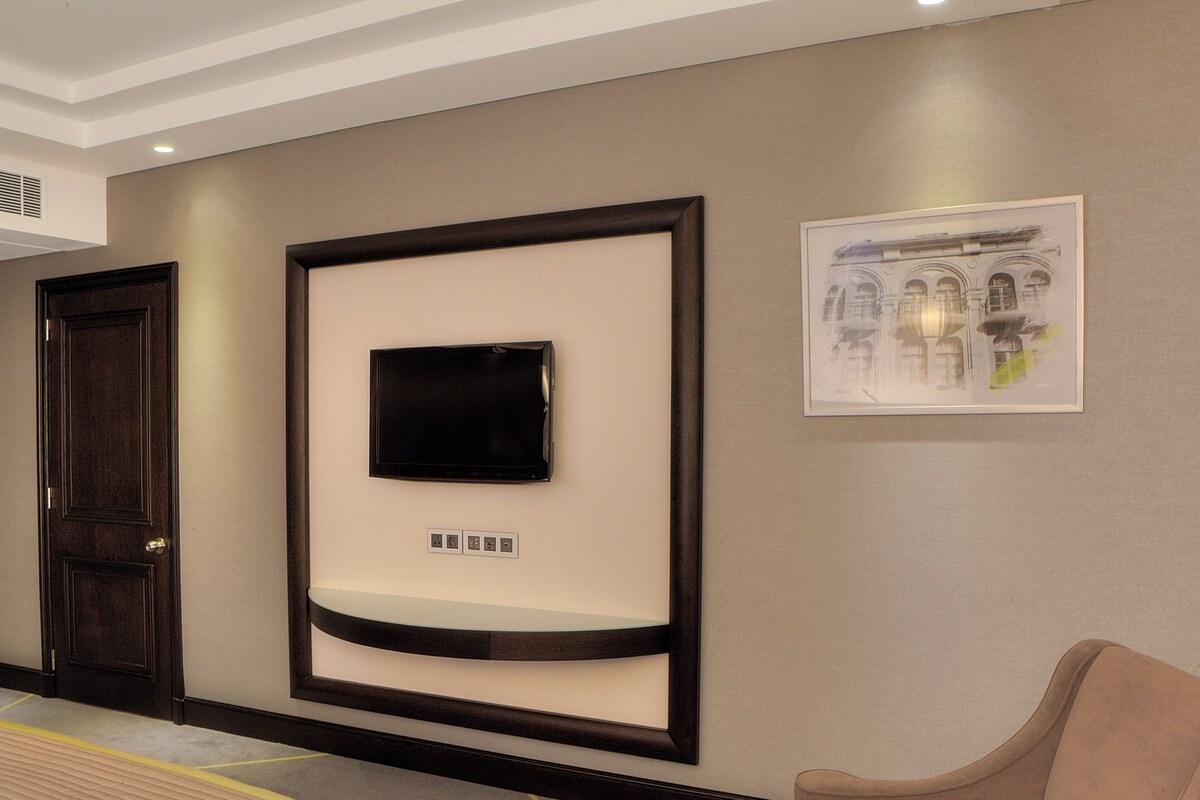 Un vestíbulo de hotel con una obra de arte enmarcada, un televisor de pantalla plana y un área de descanso.