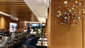A modern restaurant with a long counter, multiple seating areas, and a decorative wall piece.