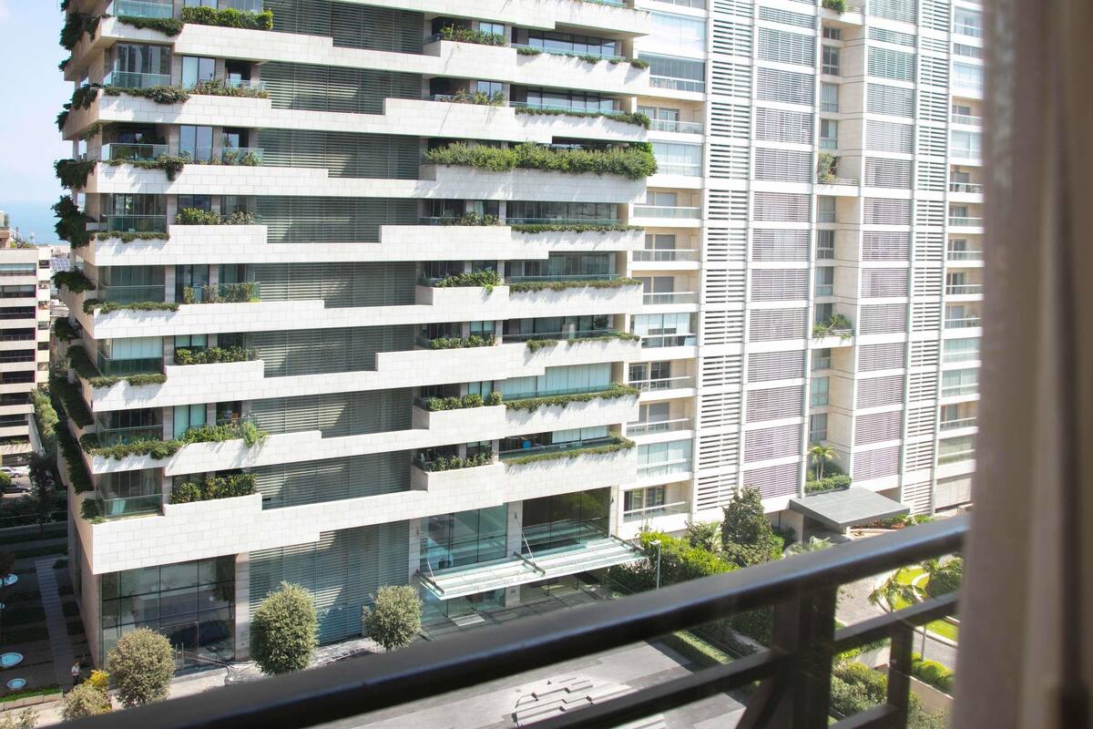 A modern high-rise building with multiple balconies, large windows, and a glass entrance.