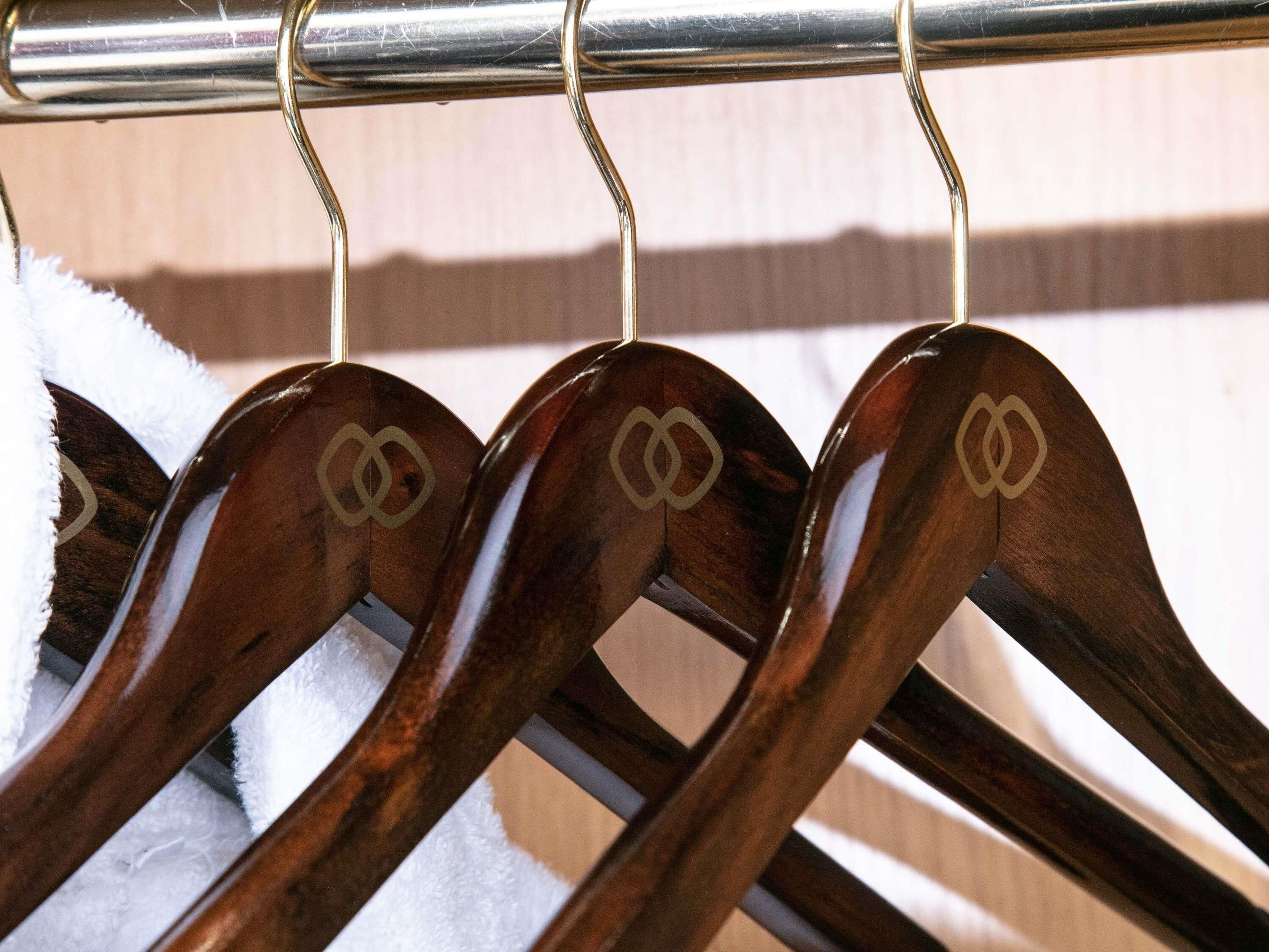 A wooden hanger rack with three hangers, each featuring a double infinity symbol.