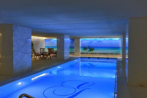 A swimming pool with a view of a beach and boats, surrounded by marble pillars and a seating area. - Sofitel Beirut Le Gabriel (Beirut)