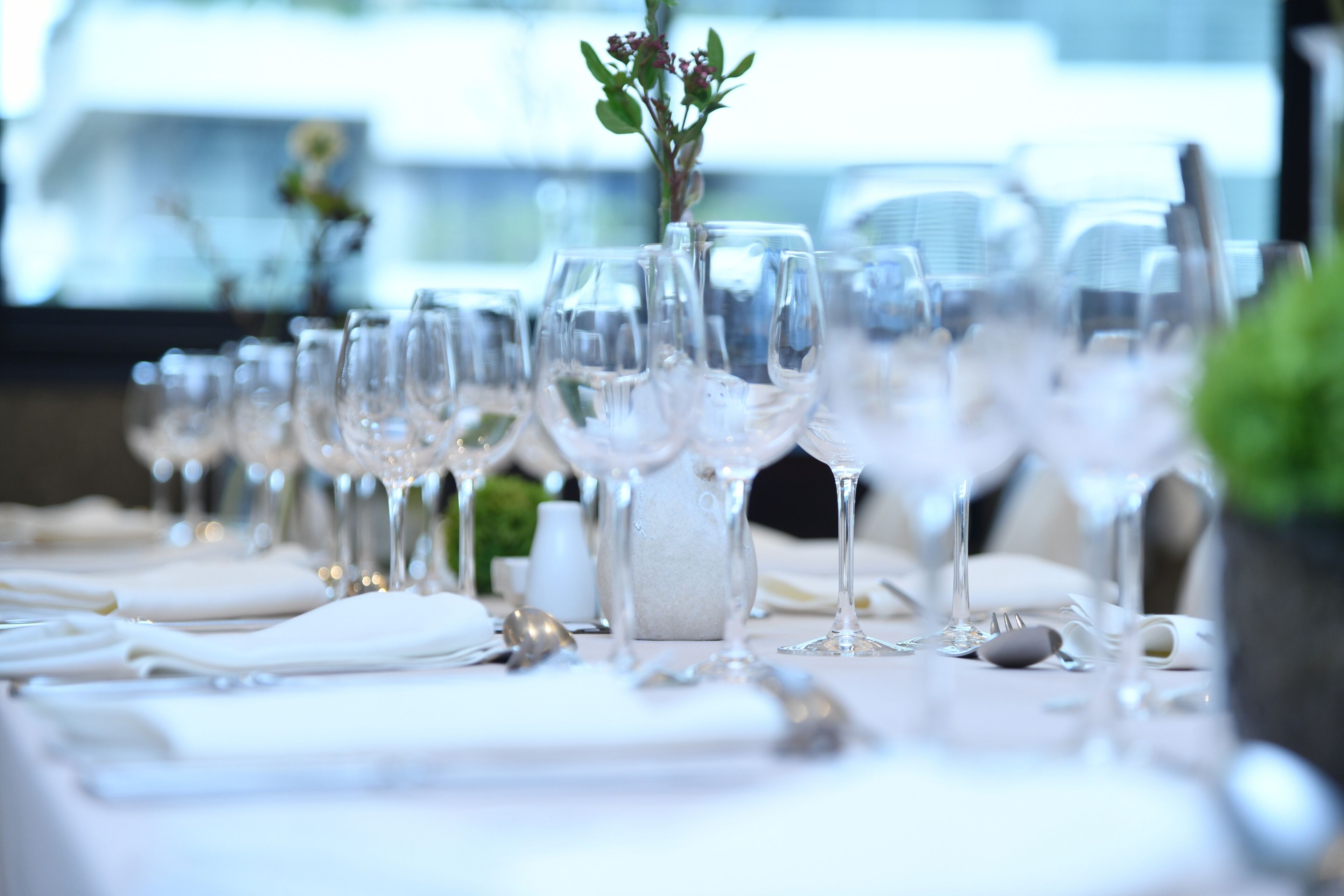 A table set with multiple wine glasses, plates, and cutlery, indicating a formal dining arrangement.