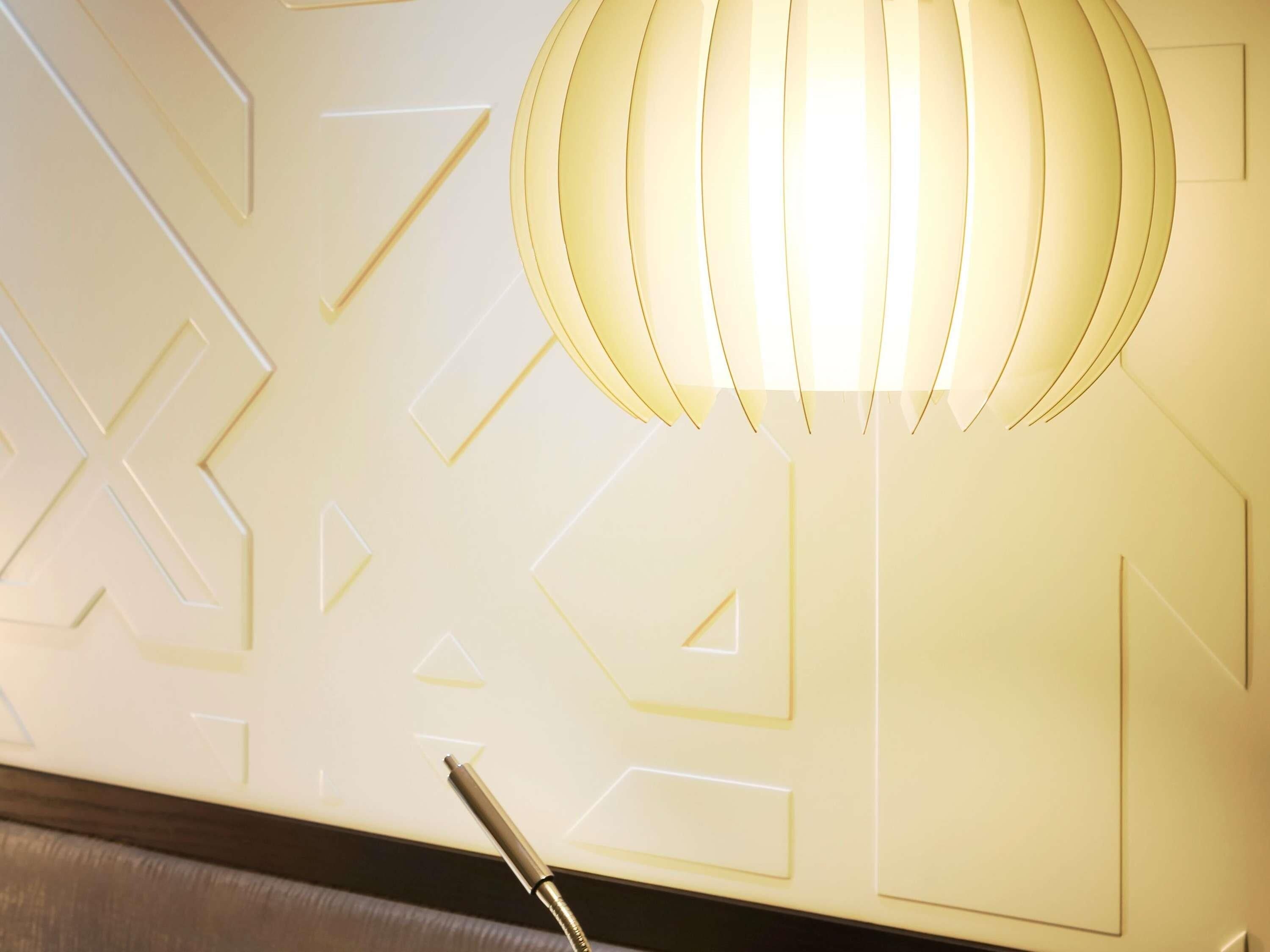 A wall with geometric patterns and a hanging light fixture.