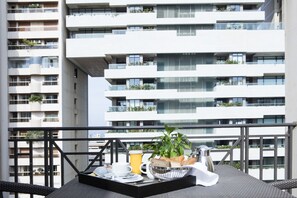 Un balcón con una mesa para el desayuno, que incluye un bol de pan, una taza y una jarrilla.