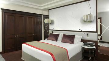 A hotel room with a large bed, a desk, a chair, a wardrobe, and a wall-mounted artwork.
