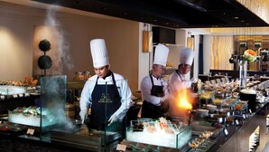 Een buffetopstelling met koks die eten bereiden, diverse gerechten en een modern interieur.
