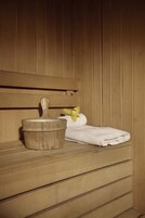 A wooden bench with a towel and a wooden bucket.