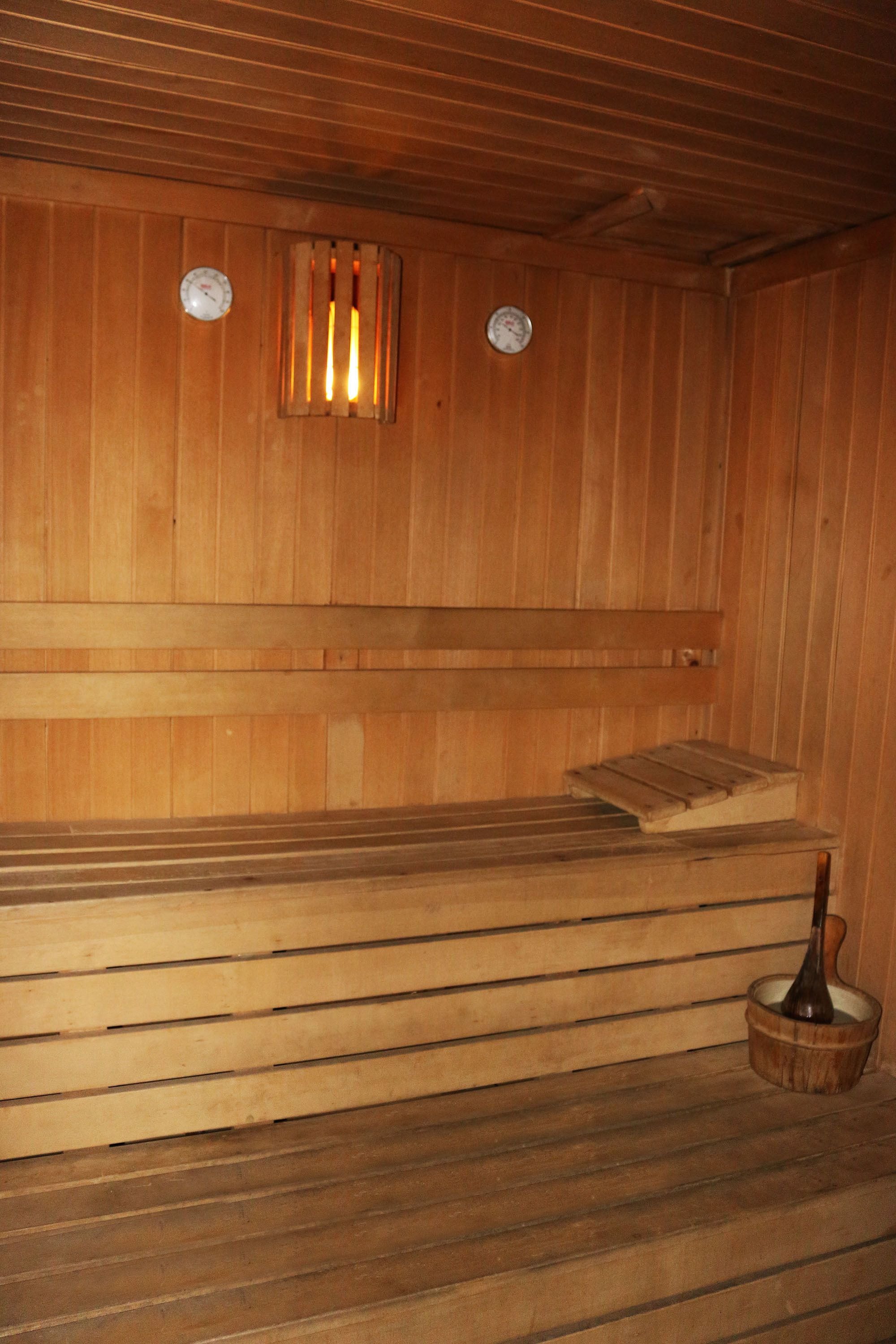 A wooden sauna with benches and a wooden bucket.