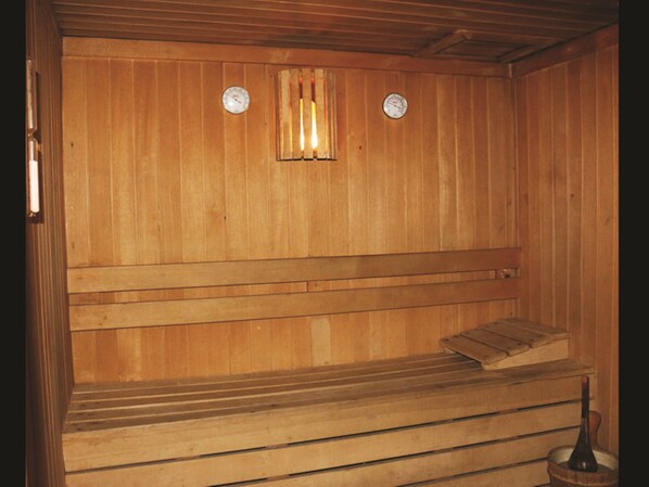 Una sauna de madera con bancos y un asiento de banco.