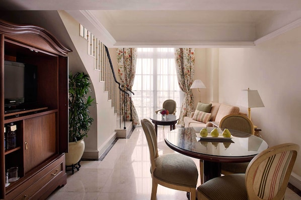A dining area with a round table, chairs, a television, and a potted plant. - Hotel Gran Mahakam (Jakarta)