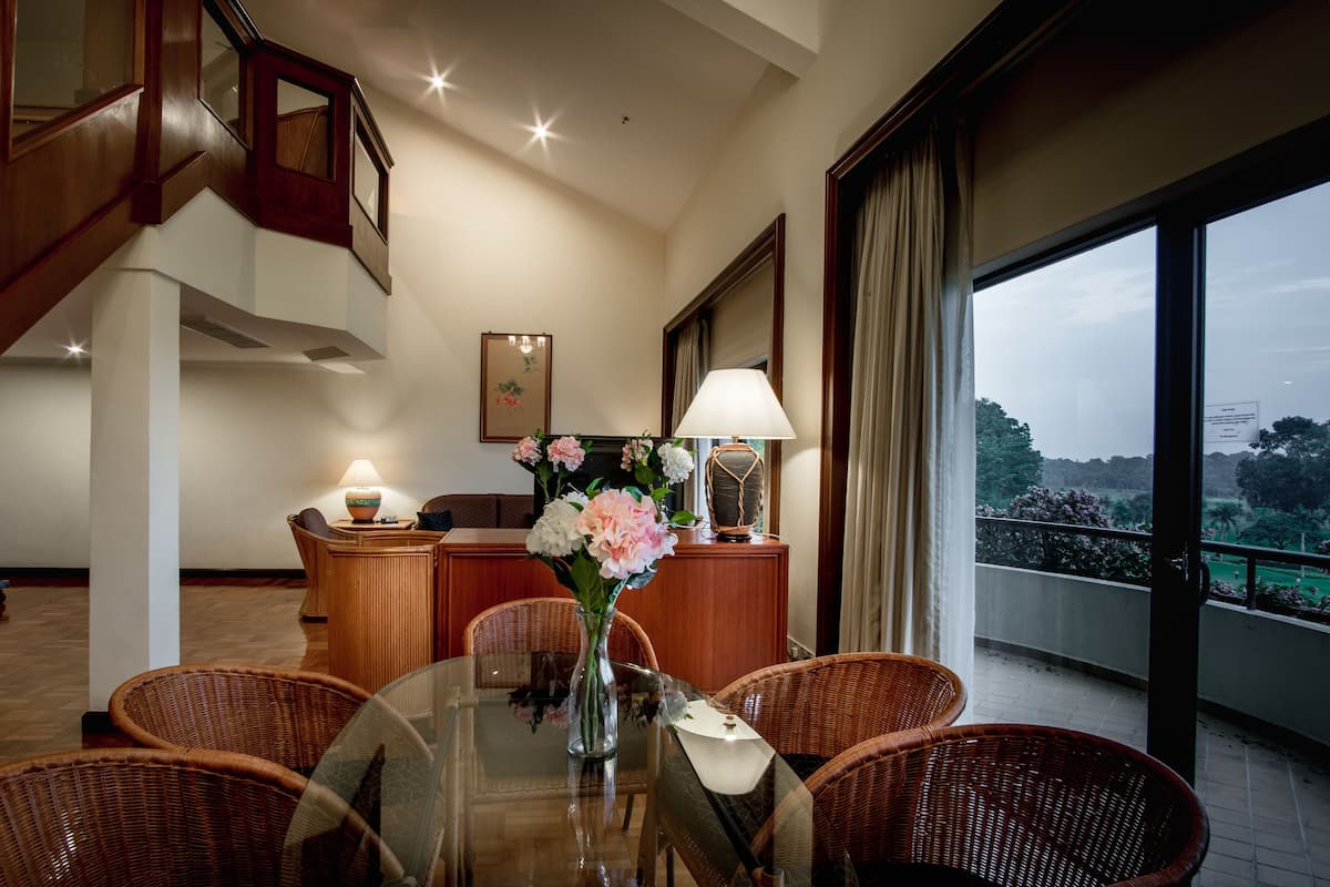 A dining area with wicker chairs, a glass table, and a vase of flowers.
