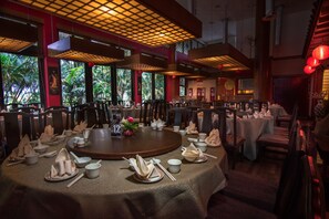 A restaurant with round tables set for dining, featuring traditional Chinese tableware and a warm, inviting atmosphere with red accents and natural light. - Le Grandeur Palm Resort Johor (Senai)