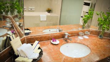 Un baño con lavamanos de mármol, un espejo grande y una cabina de ducha de vidrio.