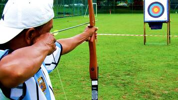 A person aiming a bow at an archery target.
