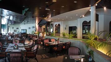A restaurant with multiple dining tables and chairs, a ceiling fan, and a view of the outdoors.