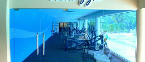 A gym with a large glass wall, exercise equipment, and a sign that reads "Palm Gym".