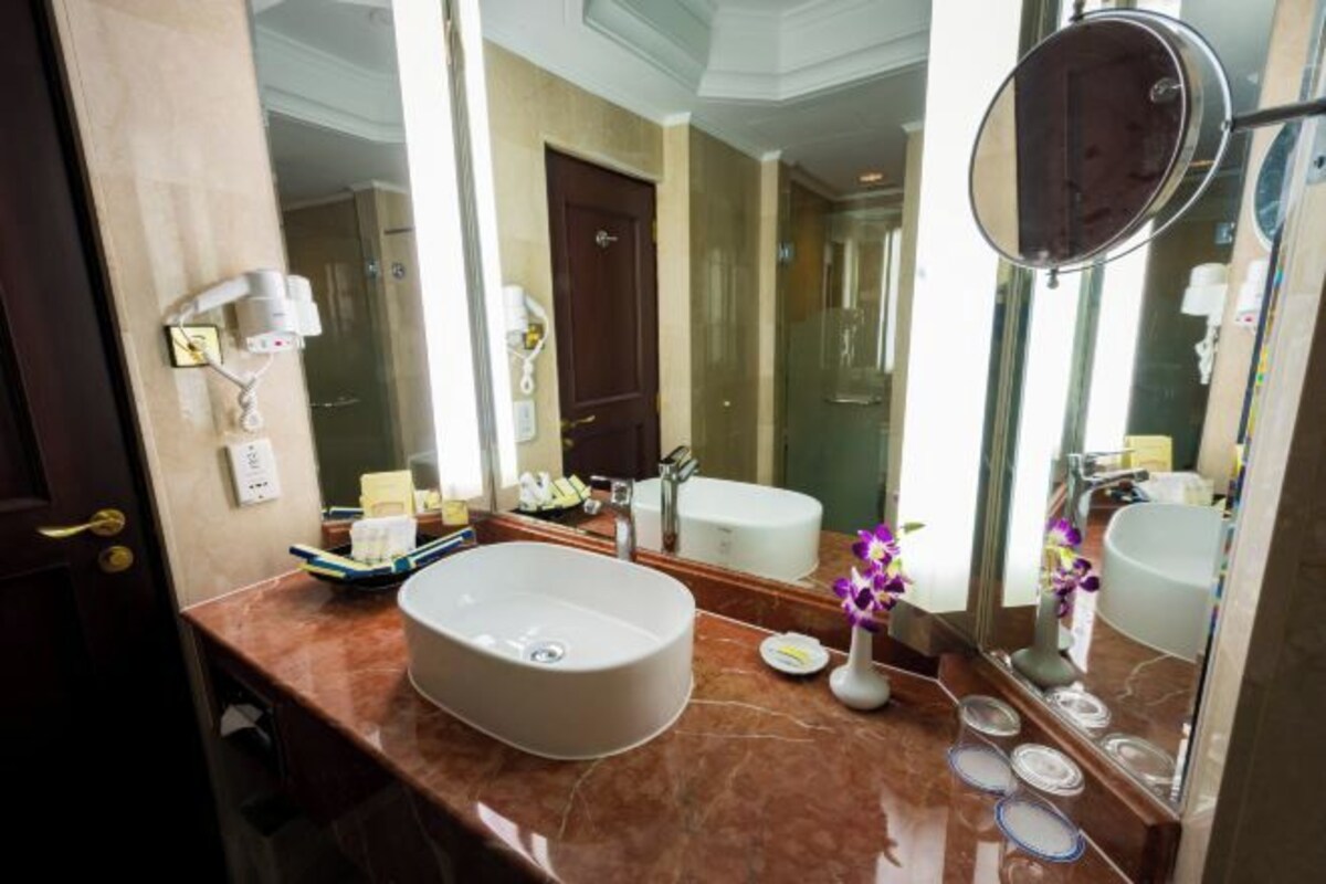 A bathroom with a large mirror, a sink, and a shower area.
