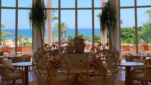 A dining area with a view of the sea, featuring wicker furniture and a large hanging light fixture. - Marina Smir Hotel & Spa (Allyene)