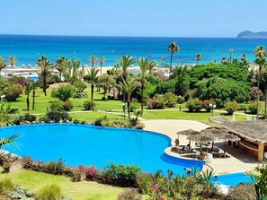 Un resort con una amplia piscina, zona de playa y vista al océano.