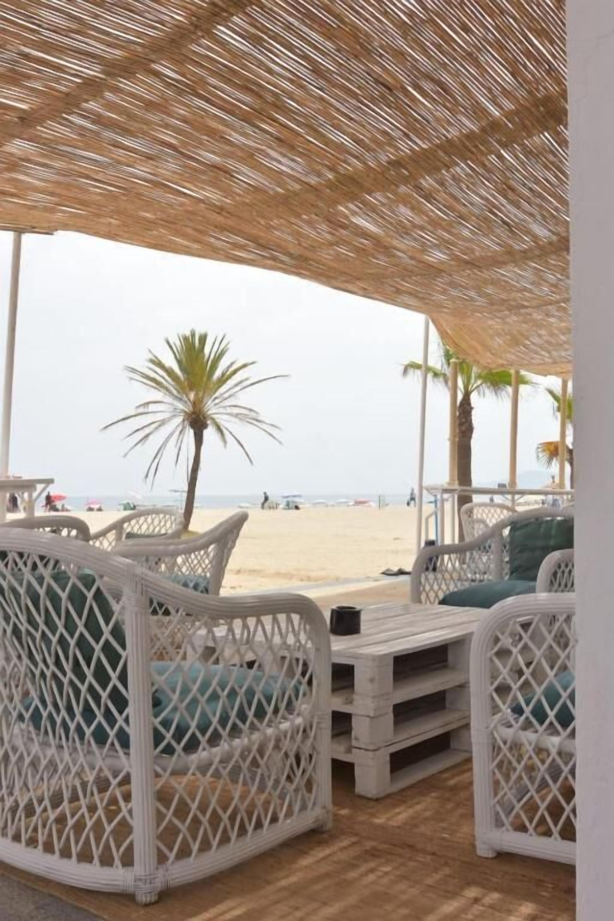 Een strandlounge met rieten meubilair en uitzicht op het strand.
