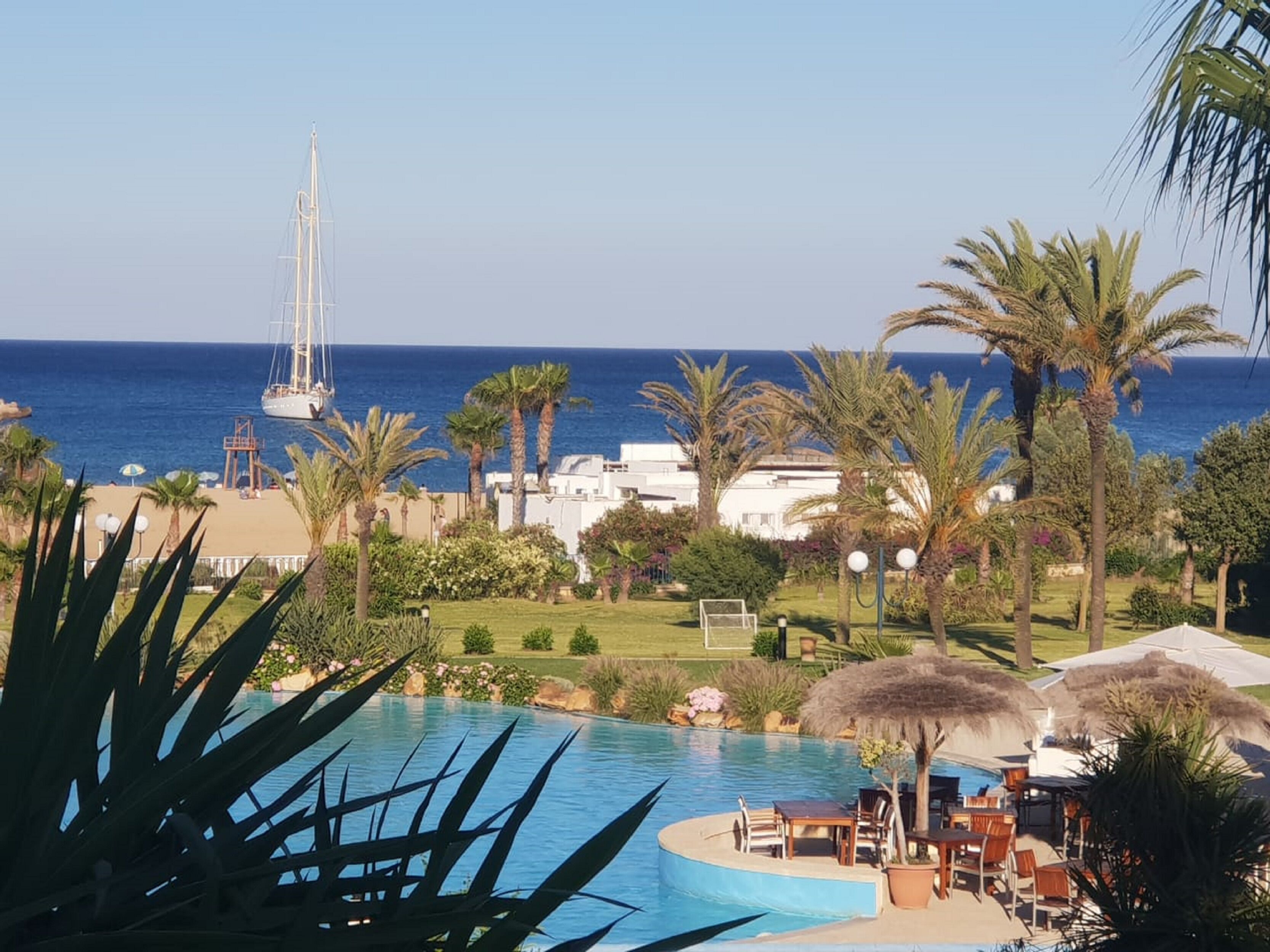Zona de piscina amb vista a l'oceà i un veler.