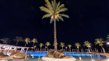 Una piscina al aire libre, sombrillas, sillones reclinables de piscina