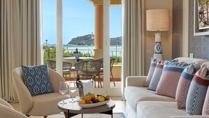 A hotel room with a balcony, a dining table with fruit, and a sofa with patterned cushions. - Almar Timi Ama Villasimius (Villasimius)