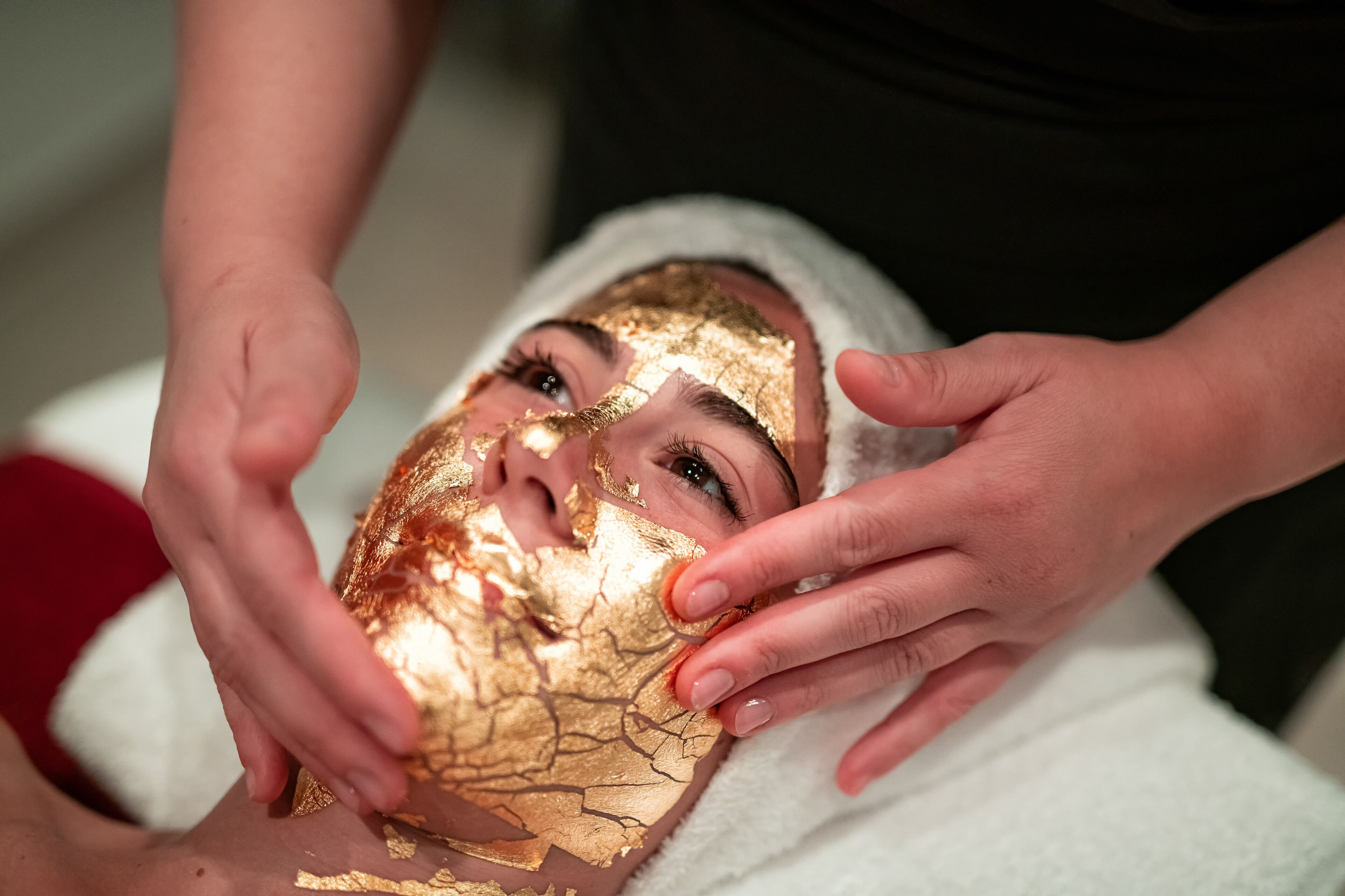 A person receiving a facial treatment with a gold mask.