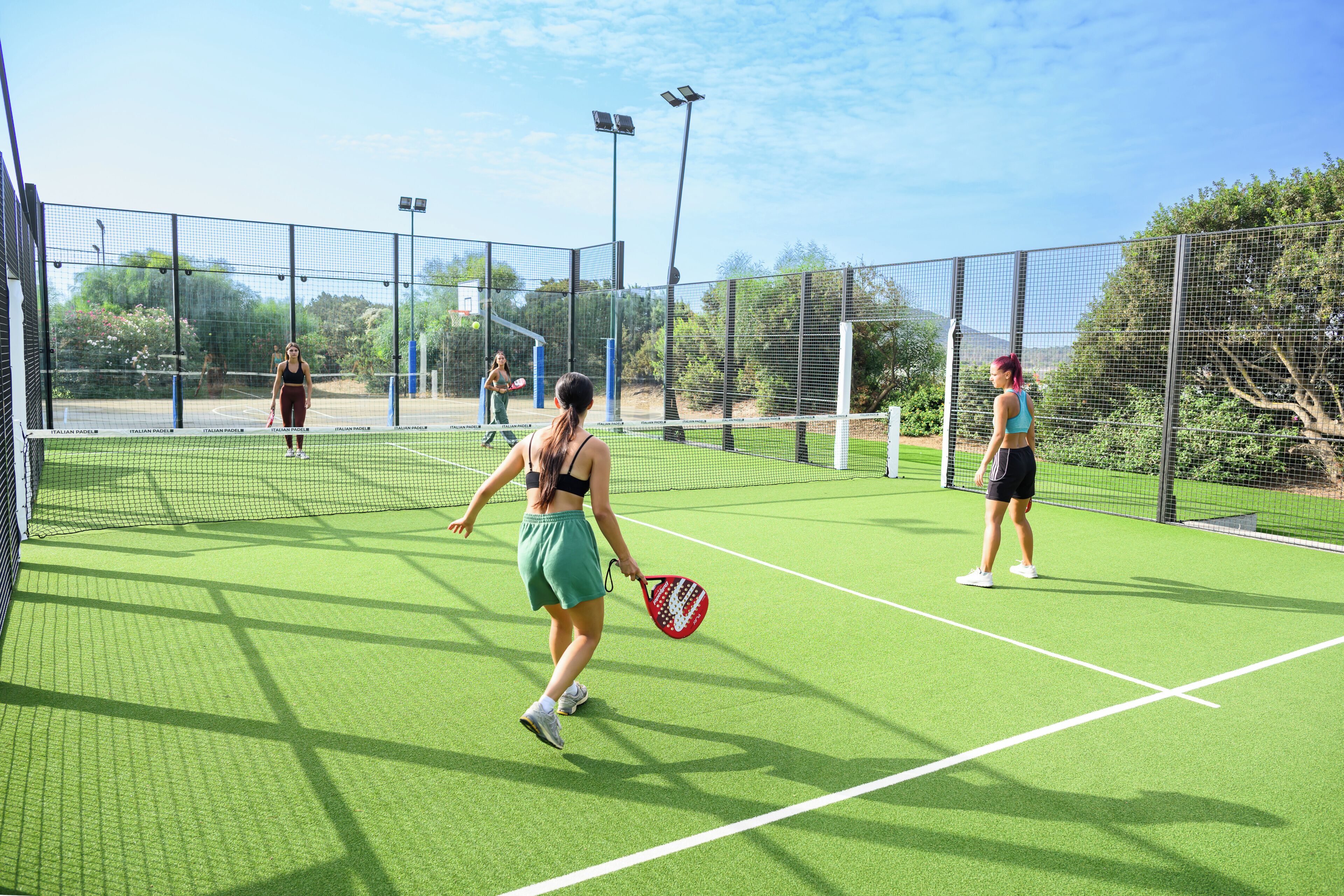 Una cancha de tenis interior con red, jugadores y cielo despejado.