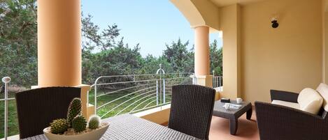 A balcony with wicker furniture, a white table, and a cactus centerpiece.