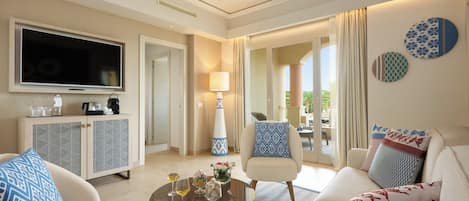 A modern hotel room with a flat-screen TV, a sofa, a coffee table with drinks, a cabinet, and a view of the outdoors.