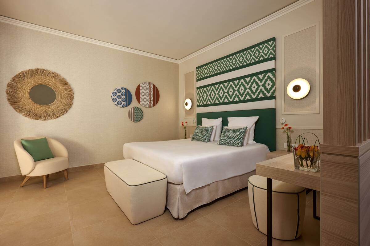 A modern bedroom with a bed, a chair, a desk, and decorative wall art.