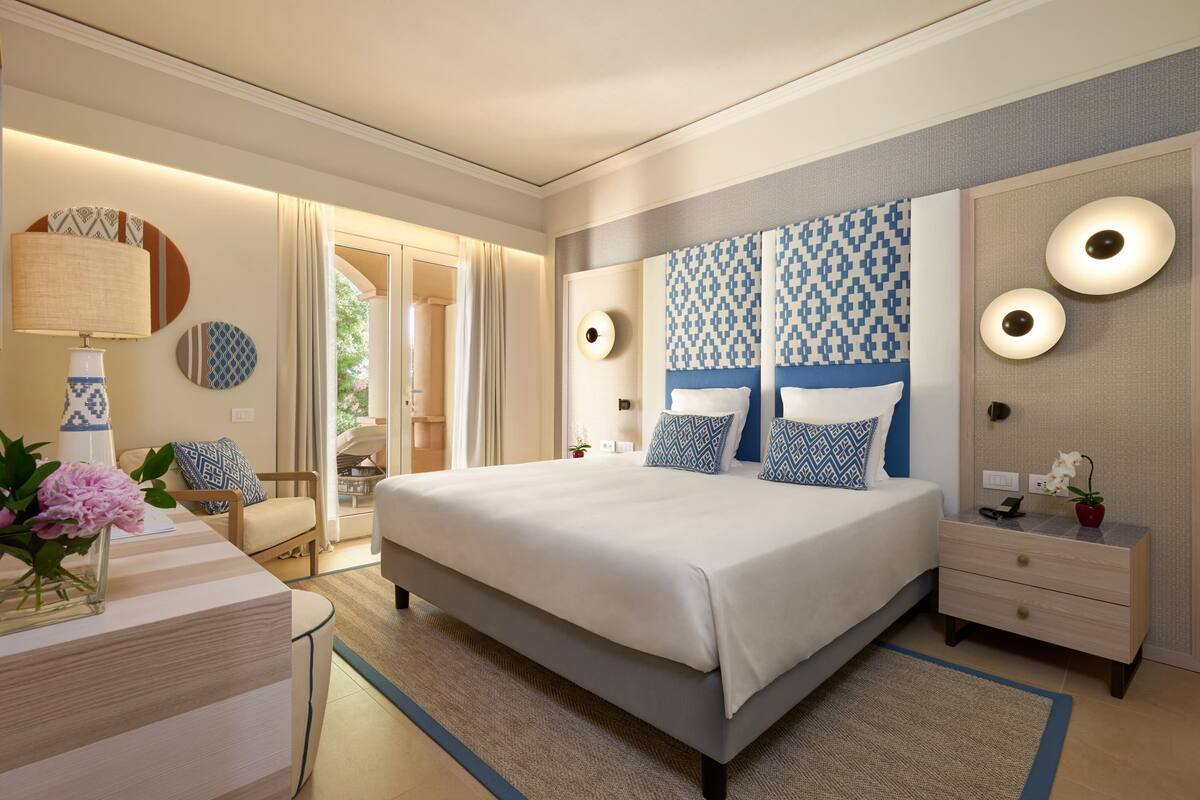 A modern bedroom with a large bed, bedside tables, a nightstand, and a mirror.