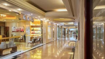 A corridor with a glass storefront, seating area, and a staircase leading to another level.