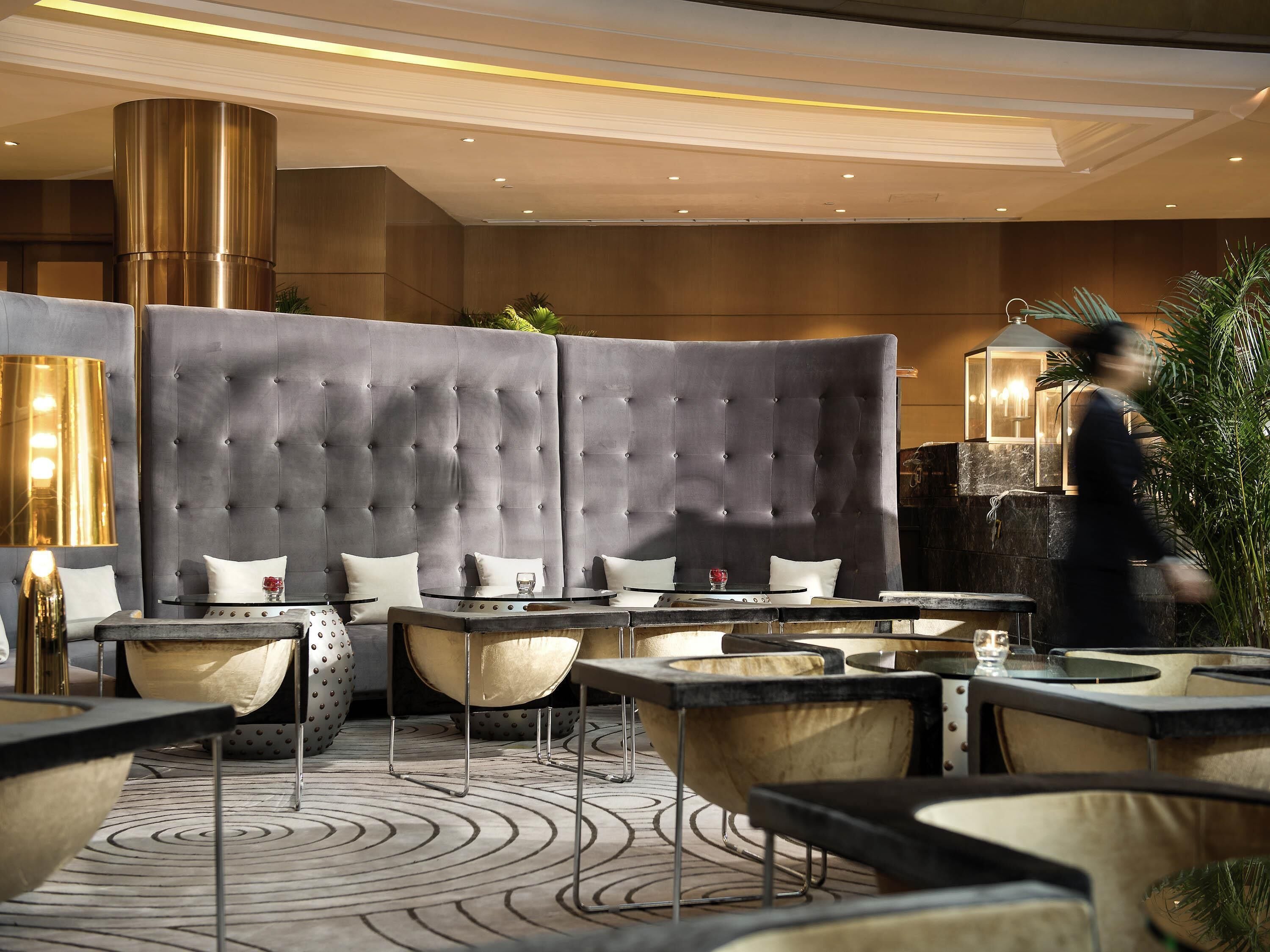 A modern indoor seating area with tufted headboards, cushioned chairs, and a patterned floor.