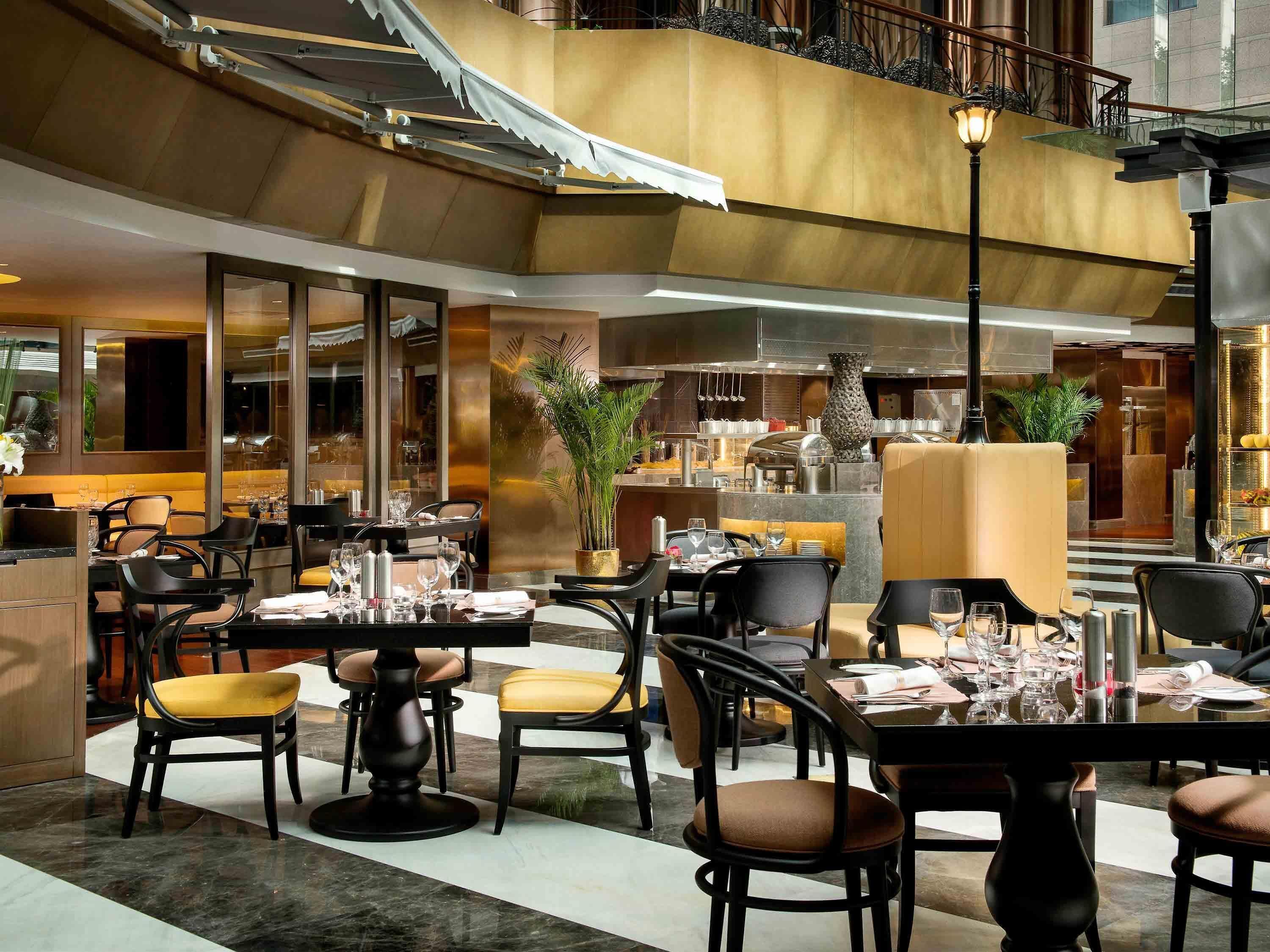 A restaurant with tables set for dining, a bar area, and a view of the cityscape.