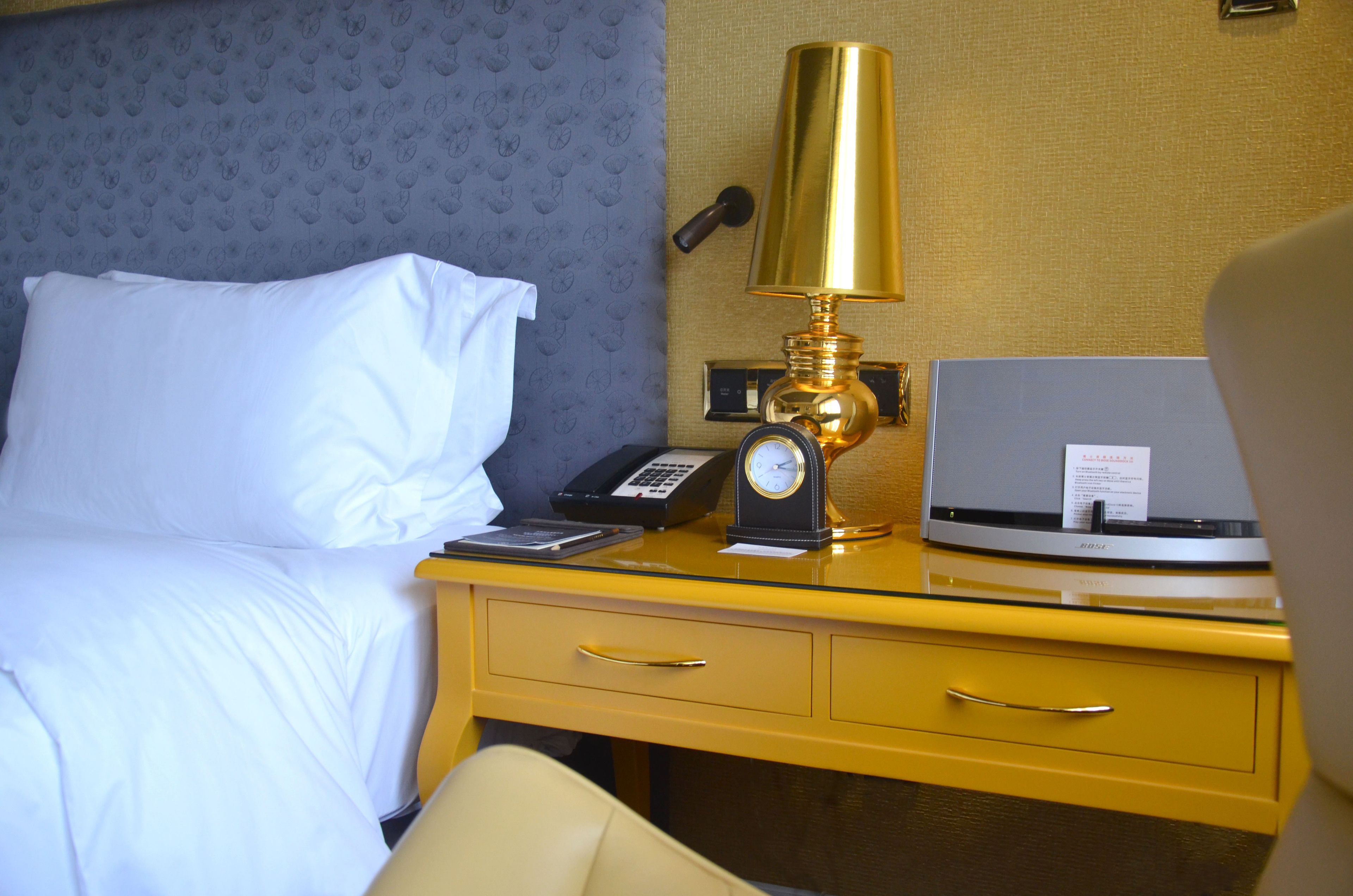 Een hotelkamer met een bed, een bureau met lamp, een telefoon en een laptop.