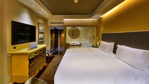 Habitación de hotel con una cama grande, un televisor en un mueble amarillo y vista al baño.