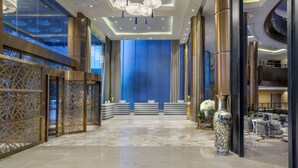 Un vestíbulo amplio con una pared azul decorativa, un mostrador de recepción y un jarrón grande.