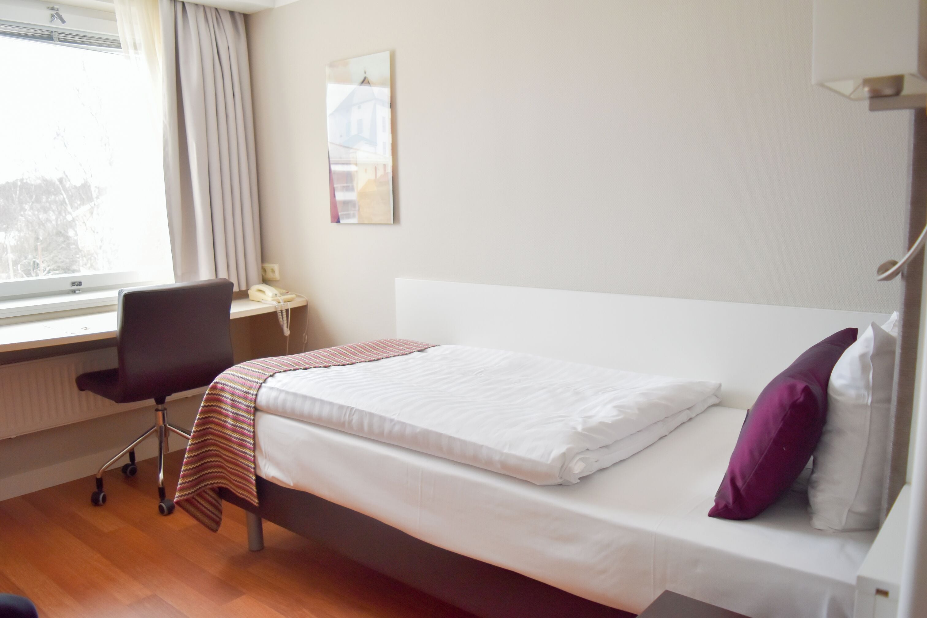 A hotel room with a bed, a desk, and a chair.