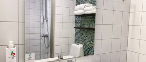 A bathroom with a white sink, a mirror, a shower, and a towel rack.