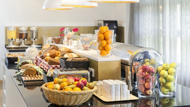 Un bufé con diversas frutas, bollería y bebidas.