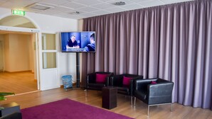 A modern waiting area with leather sofas, a large flat-screen TV, and a purple carpet. - Good Morning+ Hägersten (Hägersten)