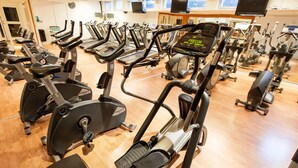 Un gimnasio con varias cintas de correr, bicicletas estáticas y máquinas elípticas.
