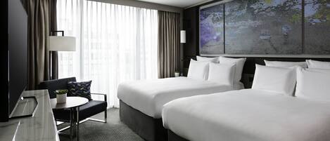 Habitación de hotel con dos camas, un escritorio, una silla, un televisor y un ventanal con cortinas.