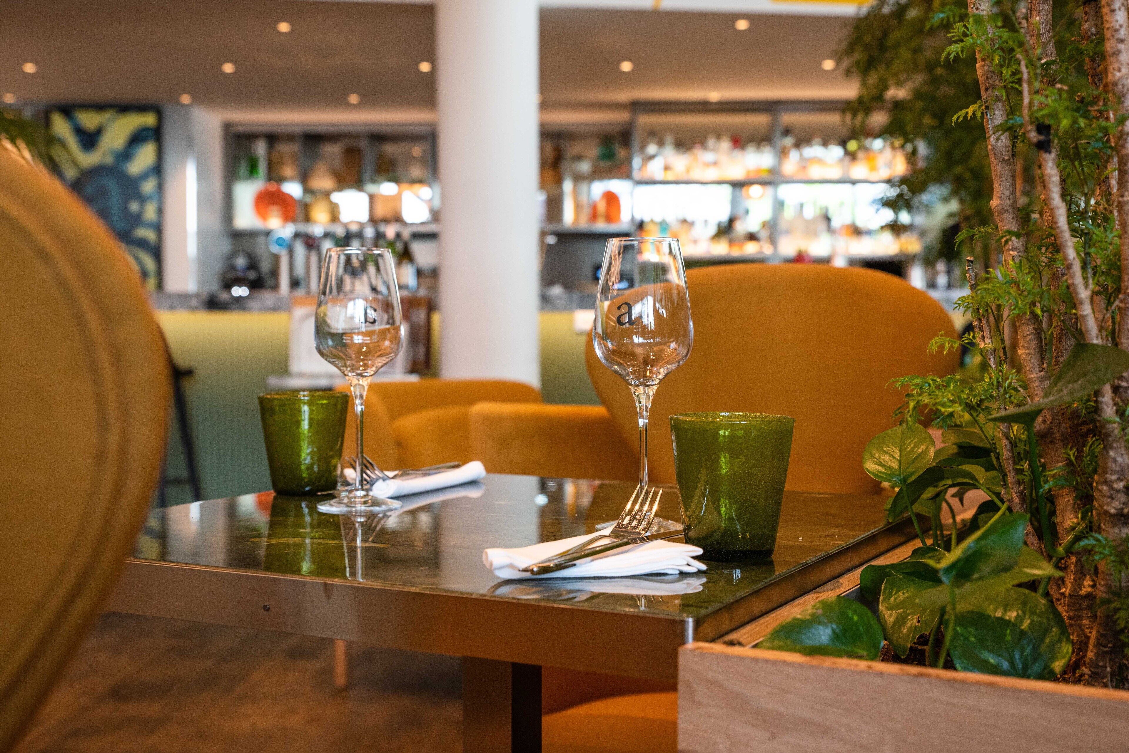 Une table de restaurant avec une tasse verte, un verre à vin et une fourchette.