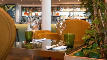 Une table de restaurant avec une tasse verte, un verre à vin et une fourchette.