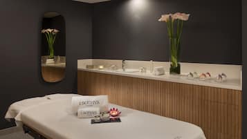 Une salle de bain moderne avec un meuble-lavabo en bois, un grand miroir et une table de massage.